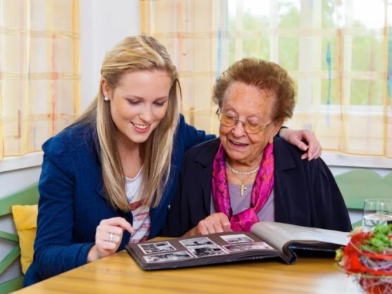 younger female and older female looking through photo book together.