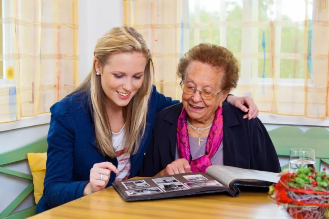 younger female and older female looking through photo book together.